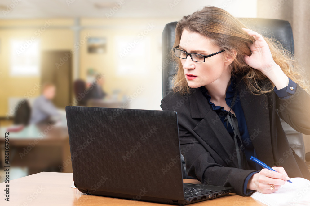 Business woman with laptop in office. Lady sits at desk. Girl works in open space office. Female employee at workplace. Business woman straightens her hair while looking at computer.