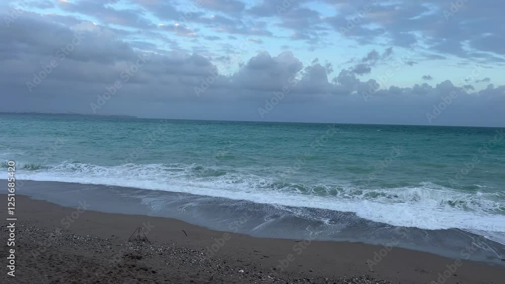 Waves crash on sandy beach as evening clouds gather over the horizon Waves crash on sandy beach as evening clouds gather over the horizon