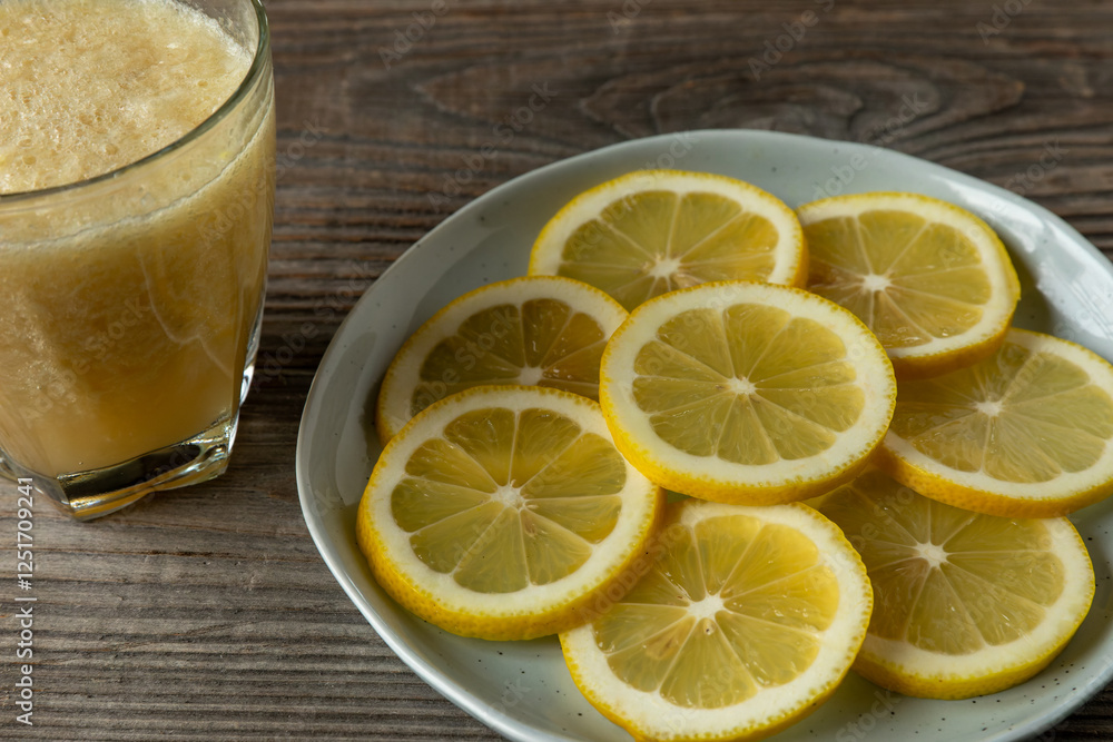 Sliced lemons with skin on a blue plate and a glass of blended whole lemon lemonade on a rustic wooden background. Sliced lemons with skin on a blue plate and a glass of blended whole lemon lemonade on a rustic wooden background.