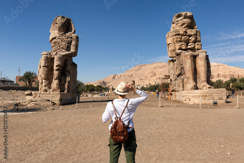  tourist girl interested in Egyptology and archaeology and gets a travel experience at the Memnon colossus Amenhotep pharaoh statue in Luxor. photo