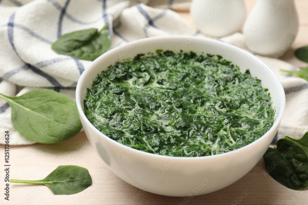 Delicious spinach sauce in bowl and leaves on wooden table, closeup Delicious spinach sauce in bowl and leaves on wooden table, closeup