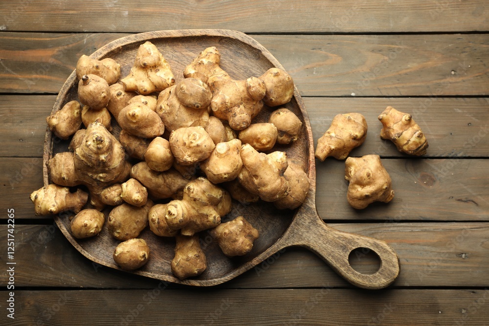 Fototapeta premium Raw Jerusalem artichokes on wooden table, top view