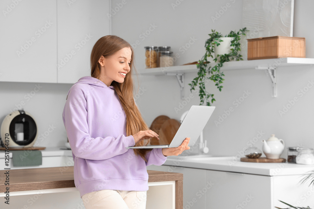 Young woman using modern laptop in kitchen Young woman using modern laptop in kitchen