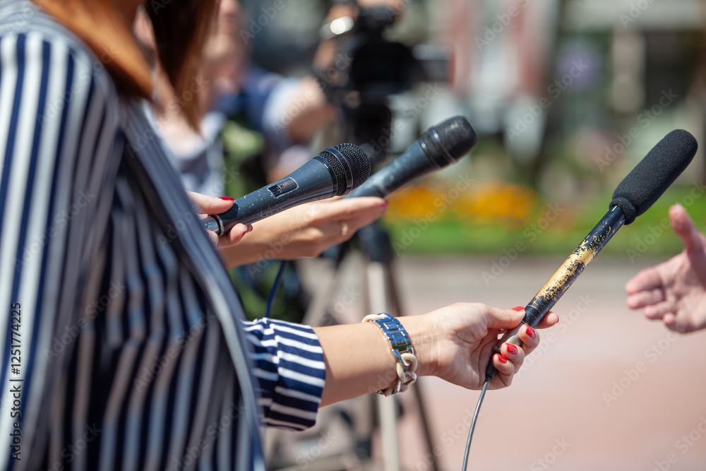 Naklejka premium Journalists and TV reporters holding microphones during a press conference or media event with a cameraman recording with television camera