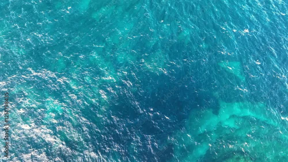 Aerial view of Vibrant blue ocean waters with gentle waves reflecting sunlight during a clear day Aerial view of Vibrant blue ocean waters with gentle waves reflecting sunlight during a clear day