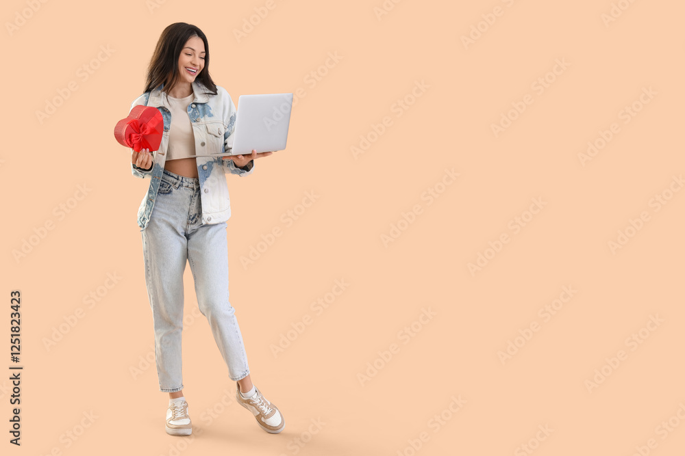 Fototapeta premium Young woman with gift and laptop video chatting with boyfriend on beige background. Online dating