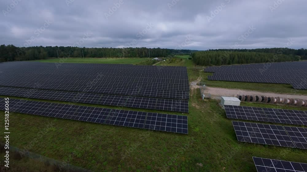 Aerial View of Solar Power Farm in Rural Landscape. Drone footage of large solar panel array in green rural area, highlighting sustainable energy solutions under cloudy sky Aerial View of Solar Power Farm in Rural Landscape. Drone footage of large solar panel array in green rural area, highlighting sustainable energy solutions under cloudy sky