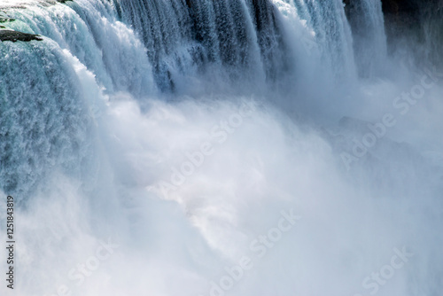 Water Cascades Dramatically Over the Edge of a Large Waterfall in a Misty Setting