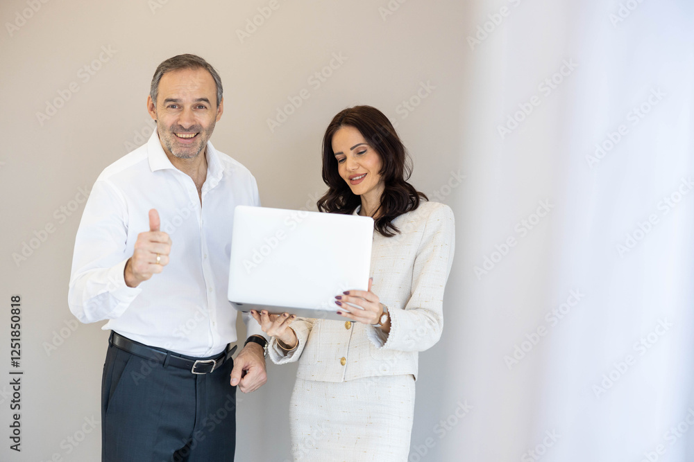 A man and a woman celebrate their discovery on a laptop, illustrating enthusiasm and camaraderie in a business setting. Man giving thumbs up A man and a woman celebrate their discovery on a laptop, illustrating enthusiasm and camaraderie in a business setting. Man giving thumbs up