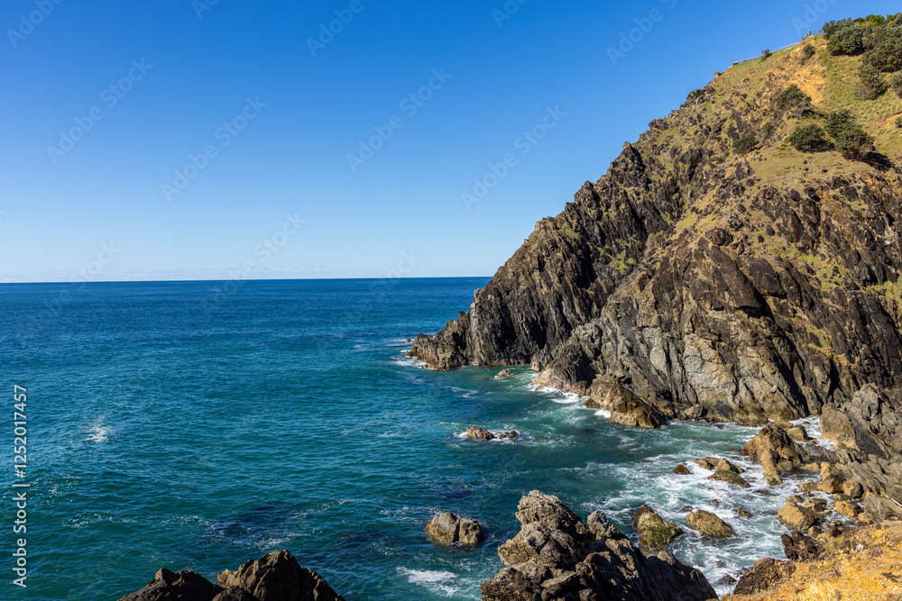 Coastal cliffside meets blue ocean under clear sky on a bright sunny day. Coastal cliffside meets blue ocean under clear sky on a bright sunny day.