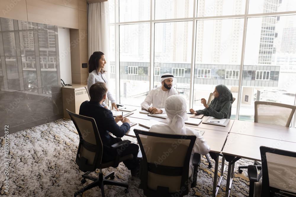 In boardroom group of intercultural businesspeople discussing various business-related topics, share strategy, planning cooperation sit at table in skyscraper office. Negotiations between shareholders In boardroom group of intercultural businesspeople discussing various business-related topics, share strategy, planning cooperation sit at table in skyscraper office. Negotiations between shareholders