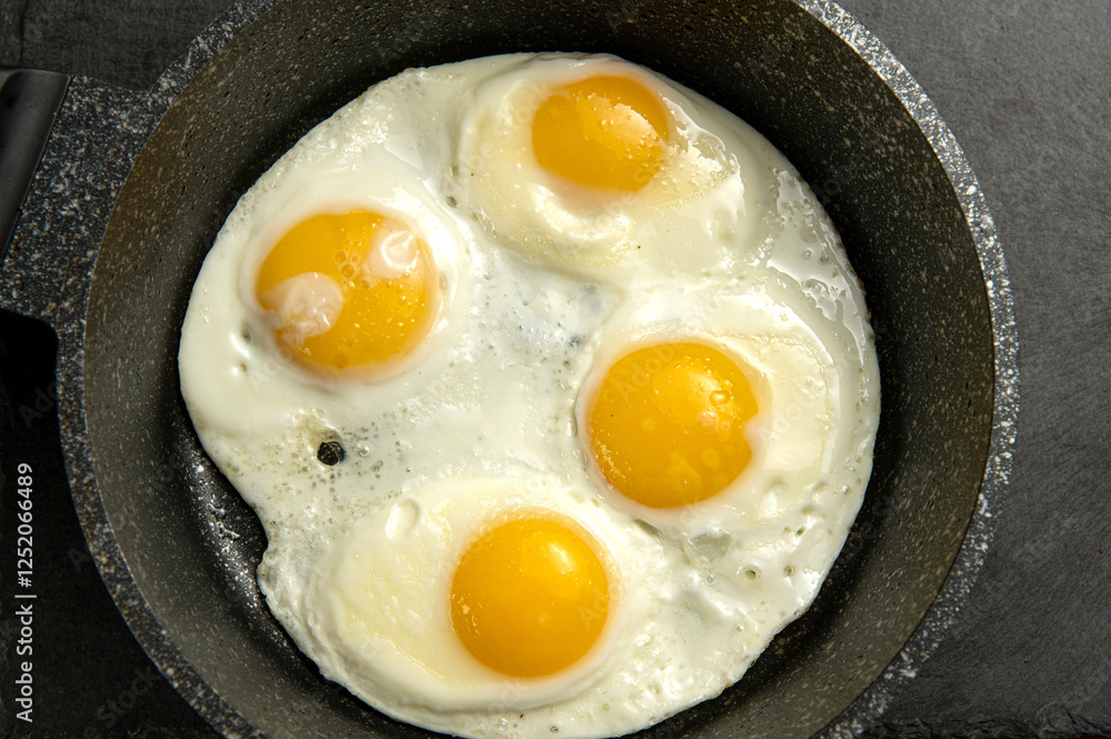 Simple breakfast: four fried eggs cooked sunny-side up in a cast iron skillet. Delicious and ready to eat! Perfect for food illustrations Simple breakfast: four fried eggs cooked sunny-side up in a cast iron skillet. Delicious and ready to eat! Perfect for food illustrations