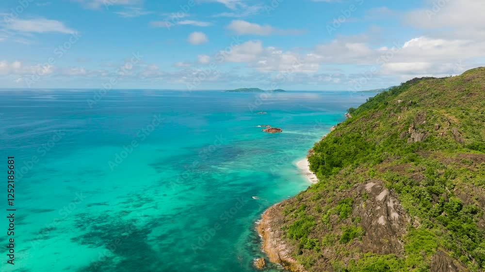 A rugged rocky coastline blends into the vibrant turquoise sea, offering a breathtaking coastal view. Praslin, Seychelles. A rugged rocky coastline blends into the vibrant turquoise sea, offering a breathtaking coastal view. Praslin, Seychelles.