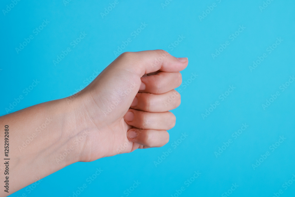Woman with visible hand veins on light blue background, closeup