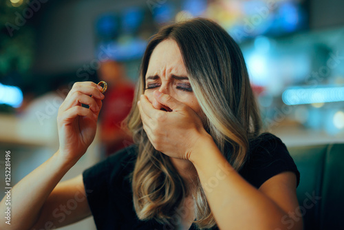 Sad Crying Divorcee Feeling Depressed and Lonely. Unhappy woman taking of her wedding ring in a restaurant

