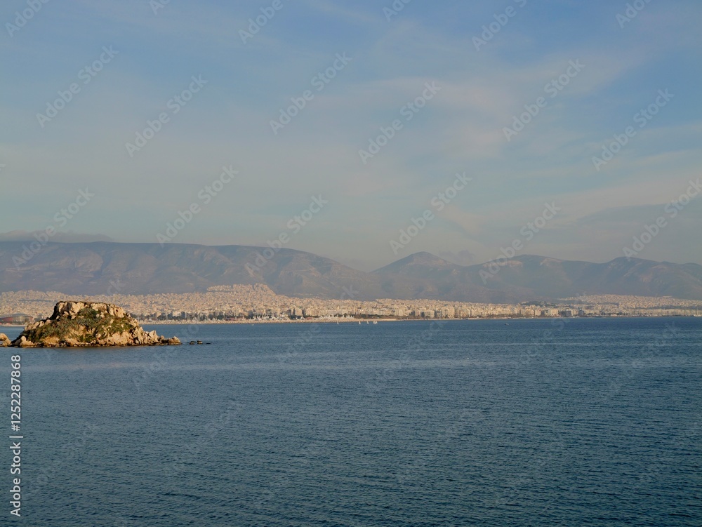 View of the seaside and Hymettus or Hymettos, a mountain range in the Athens area of Attica, from the Votsalakia beach, Piraeus, Greece View of the seaside and Hymettus or Hymettos, a mountain range in the Athens area of Attica, from the Votsalakia beach, Piraeus, Greece