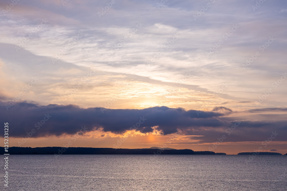 Tranquil Coastal Sunset Scene Over Calm Waters and Forest Silhouettes Tranquil Coastal Sunset Scene Over Calm Waters and Forest Silhouettes