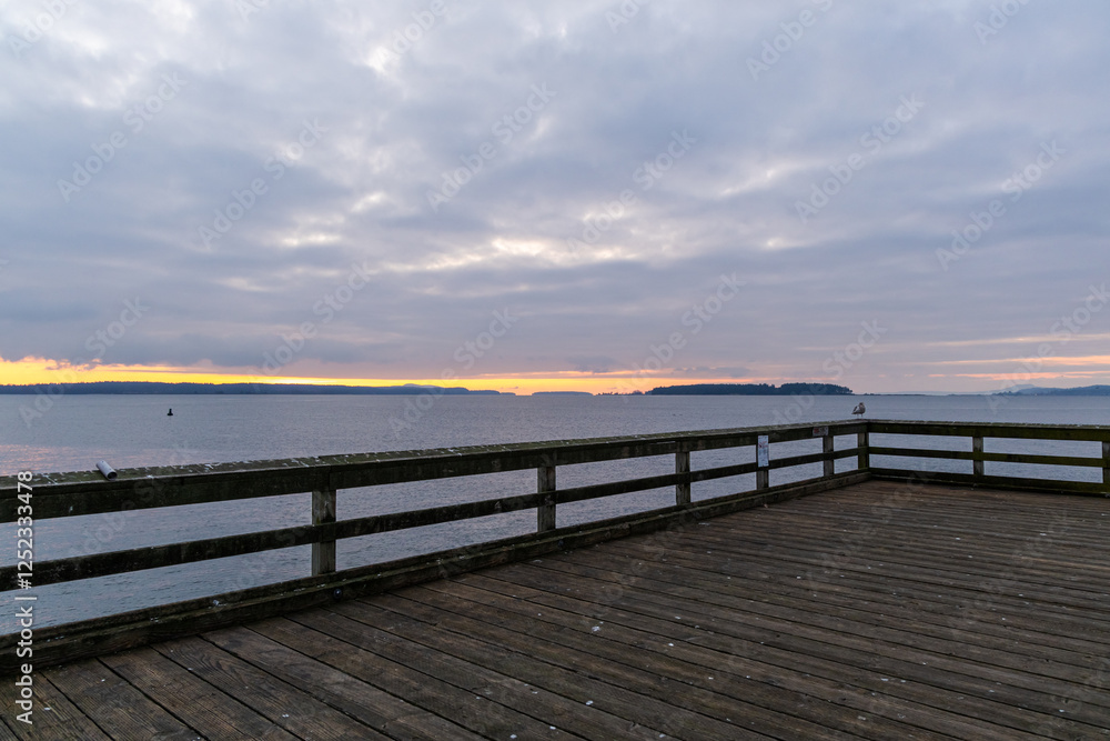 Scenic Sunset View from a Wooden Seaside Pier Over Tranquil Ocean Waves Scenic Sunset View from a Wooden Seaside Pier Over Tranquil Ocean Waves