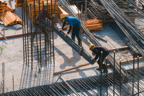 Construction Crew at Work, Dedicated workers skillfully handle steel rods and materials on bustling construction site, teamwork and essence of structural development