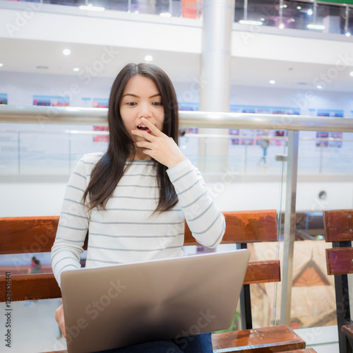 Wow ! Asian girl feels excited with the news that promotion sale through the web client side which looked from a laptop. photo