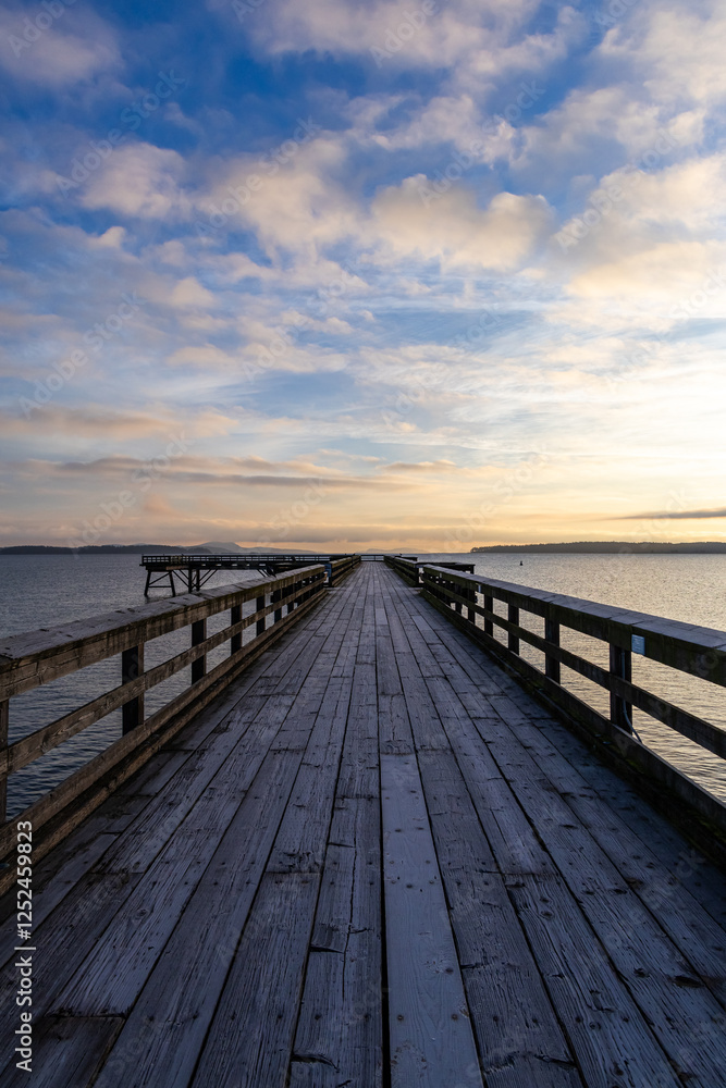 Wooden Pier Overlooking Calm Waters at Sunset with a Cloudy Sky Wooden Pier Overlooking Calm Waters at Sunset with a Cloudy Sky