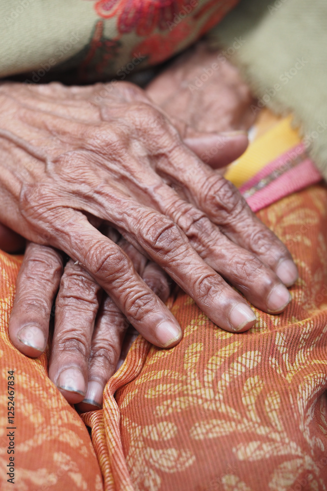 Hands of an elder woman resting gently on vibrant fabric Hands of an elder woman resting gently on vibrant fabric
