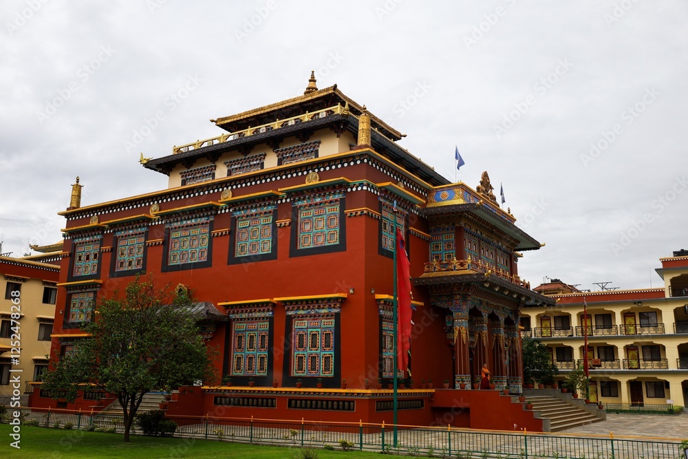 Obraz premium Traditional Tibetan architecture of Shechen Monastery in Boudha, Kathmandu, Nepal, with vibrant red walls and intricate gold details, set against a cloudy sky in Kathmandu Valley.