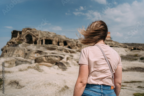 Papier peint Woman with windblown hair looking at ancient cave city in Georgia