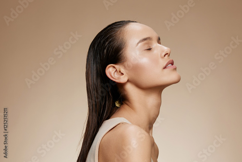 Cuadro en lienzo A serene young woman with long, wet hair poses against a neutral background, emb