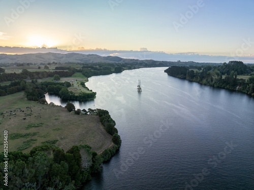 Aerial view of Waikato River, with a small boat, surrounded by farmland and hills. Tranquil scene at twilight. Karapiro, Waikato, New Zealand photo