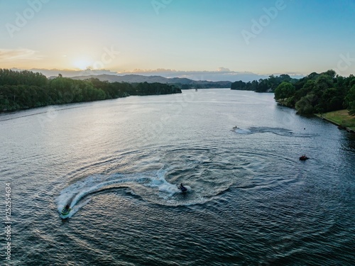 Jet skiers enjoying a tranquil Waikato River at sunset. Scenic water activity.  Karapiro, Waikato, New Zealand photo