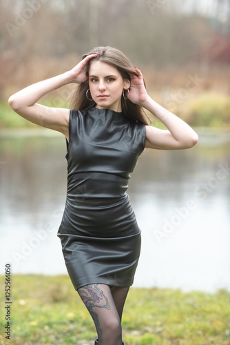 Portrait of a young beautiful brown-eyed long-haired girl in a black dress in nature.