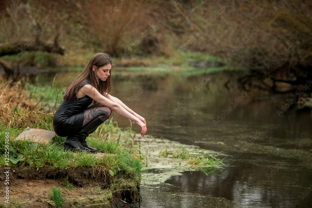 Portrait of a young beautiful brown-eyed long-haired girl in a black dress in nature.