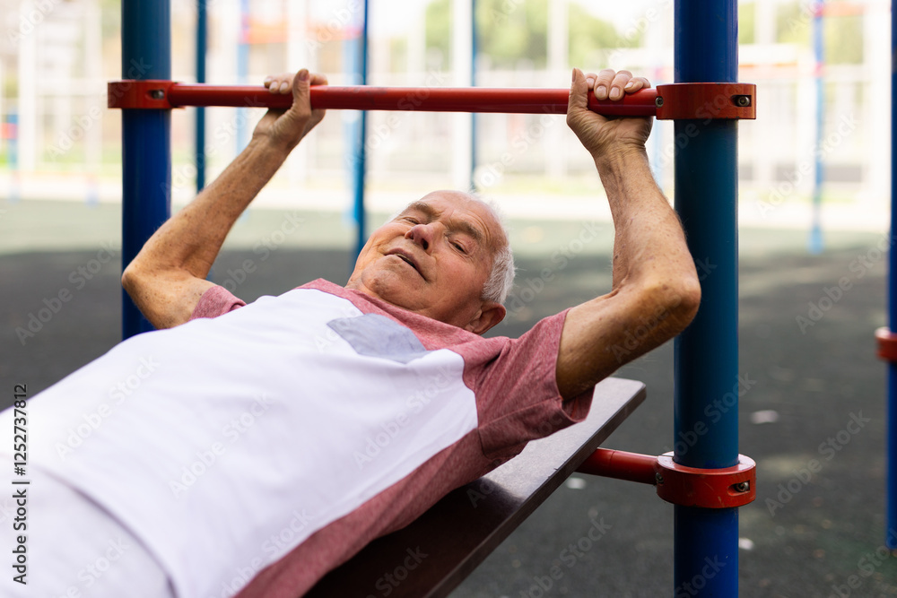 Fototapeta premium Old man doing leg raise exercise outdoors