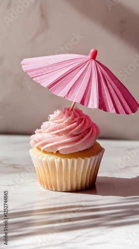 Pink frosted cupcake with a mini umbrella decoration in a bright setting