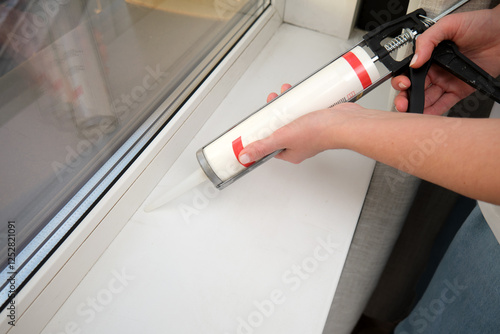 Tablou pe pânză Hand applying sealant to window sill using caulking gun