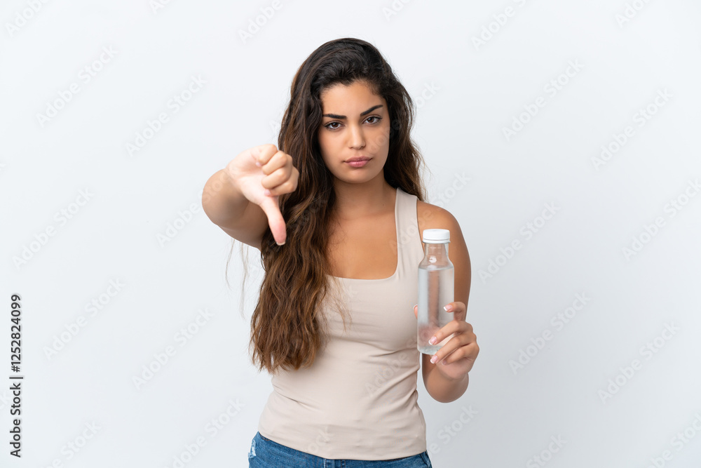 Young caucasian woman with a bottle of water isolated on white background showing thumb down with negative expression Young caucasian woman with a bottle of water isolated on white background showing thumb down with negative expression