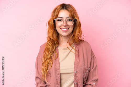 Young caucasian woman isolated on pink background With glasses with happy expression photo