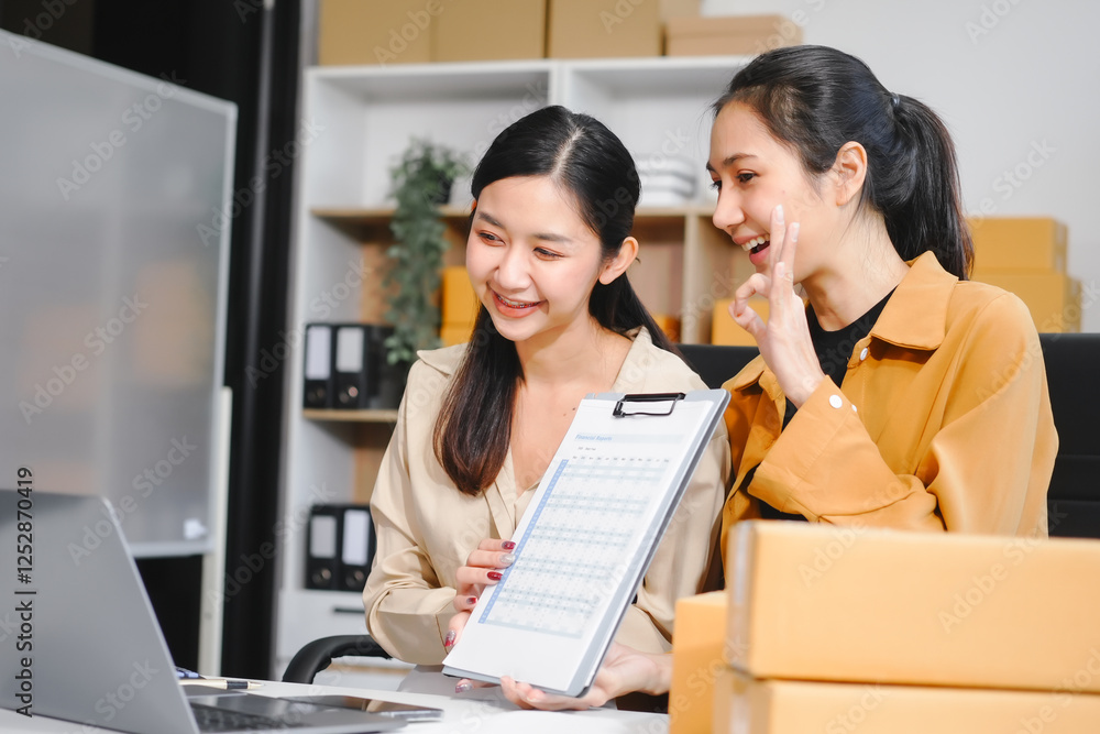 Two Asian independent women entrepreneurs start a small business, smiling while using a laptop.They manage SME delivery,online marketing,packaging, celebrating the joyful success growing e-commerce Two Asian independent women entrepreneurs start a small business, smiling while using a laptop.They manage SME delivery,online marketing,packaging, celebrating the joyful success growing e-commerce