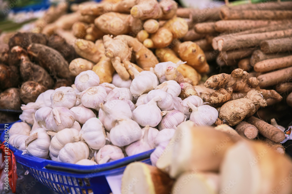 A basket of garlic and other vegetables are displayed in a market. The garlic is white and the vegetables are green A basket of garlic and other vegetables are displayed in a market. The garlic is white and the vegetables are green