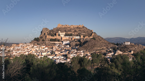 Old Spanish town with big fortified castle on hill top on sunny day, Moclin, Andalusia, Spain photo