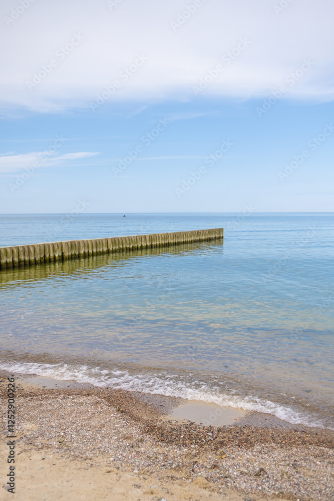 Emerald sea and blue sky on a warm summer day. Wooden buns extending into the sea and white sand. Baltic Sea, soft focus. The concept of travel, tourism Emerald sea and blue sky on a warm summer day. Wooden buns extending into the sea and white sand. Baltic Sea, soft focus. The concept of travel, tourism