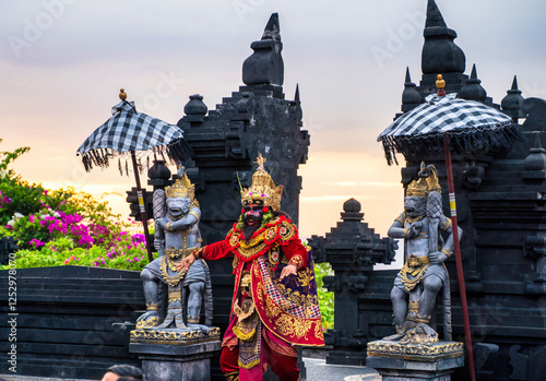 Bali, Indonesia - November 29, 2023: A vibrant depiction of Ravana during Bali’s Kecak dance, adorned in gold and red attire with a dramatic temple backdrop.