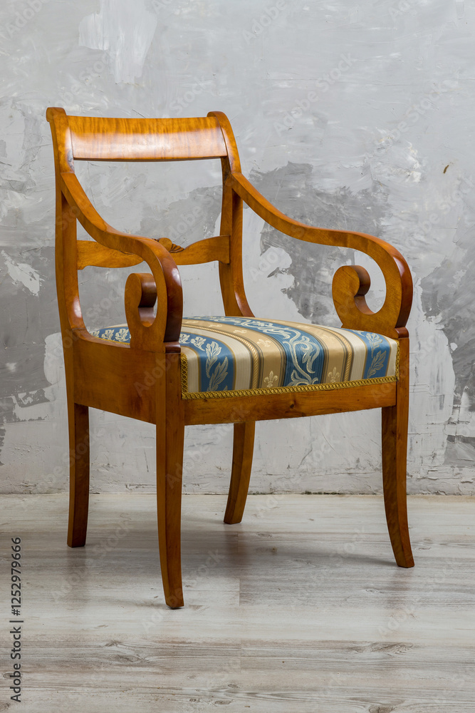 Biedermeier-style armchair in a room setting with a textured wall and wooden floor.