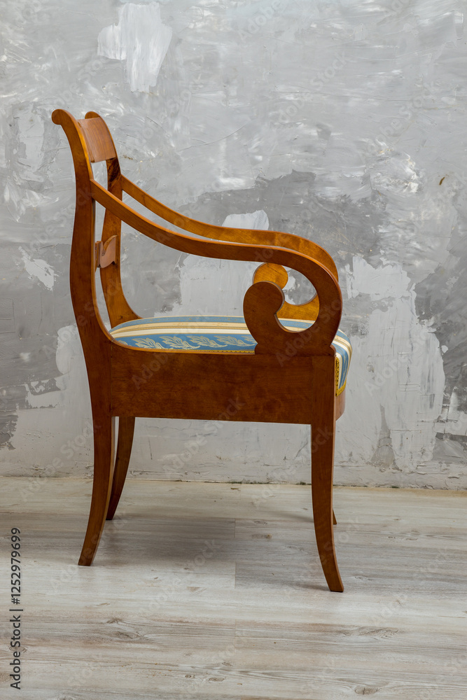 Biedermeier style armchair isolated on a white background. Light-colored wood with scrolled armrests and a striped upholstered seat. Elegant 19th-century design.