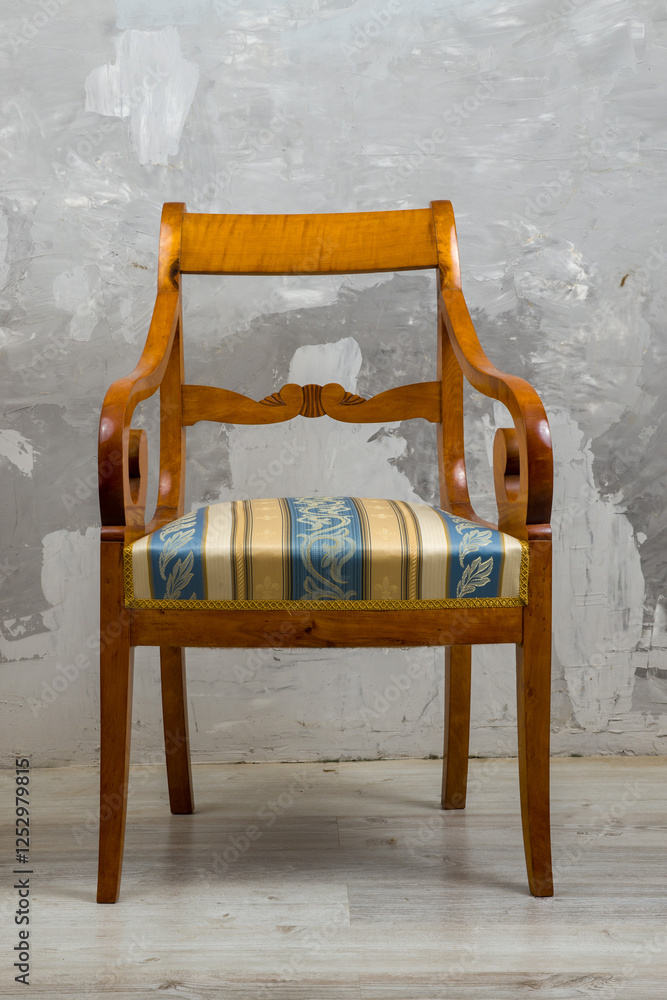 Biedermeier-style armchair in a room setting with a textured wall and wooden floor.