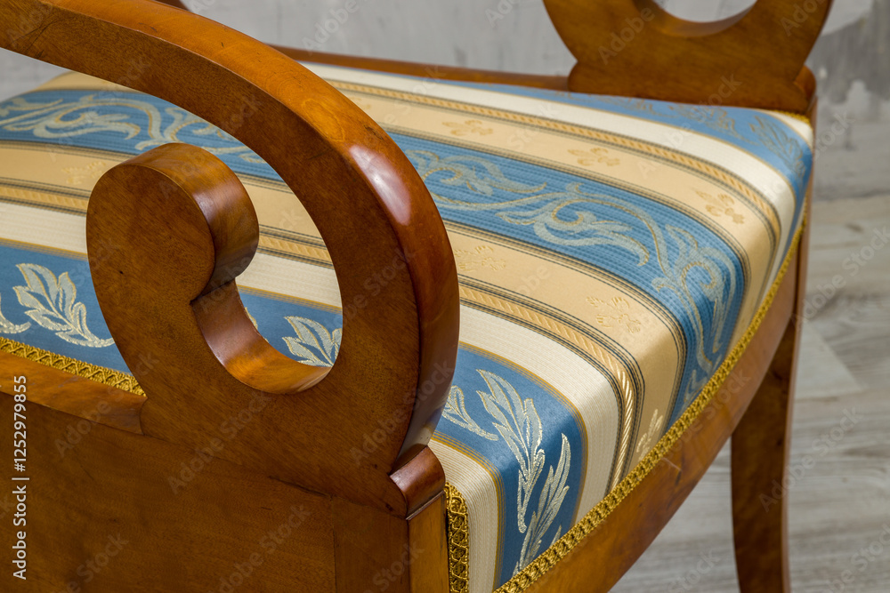Biedermeier-style armchair in a room setting with a textured wall and wooden floor.
