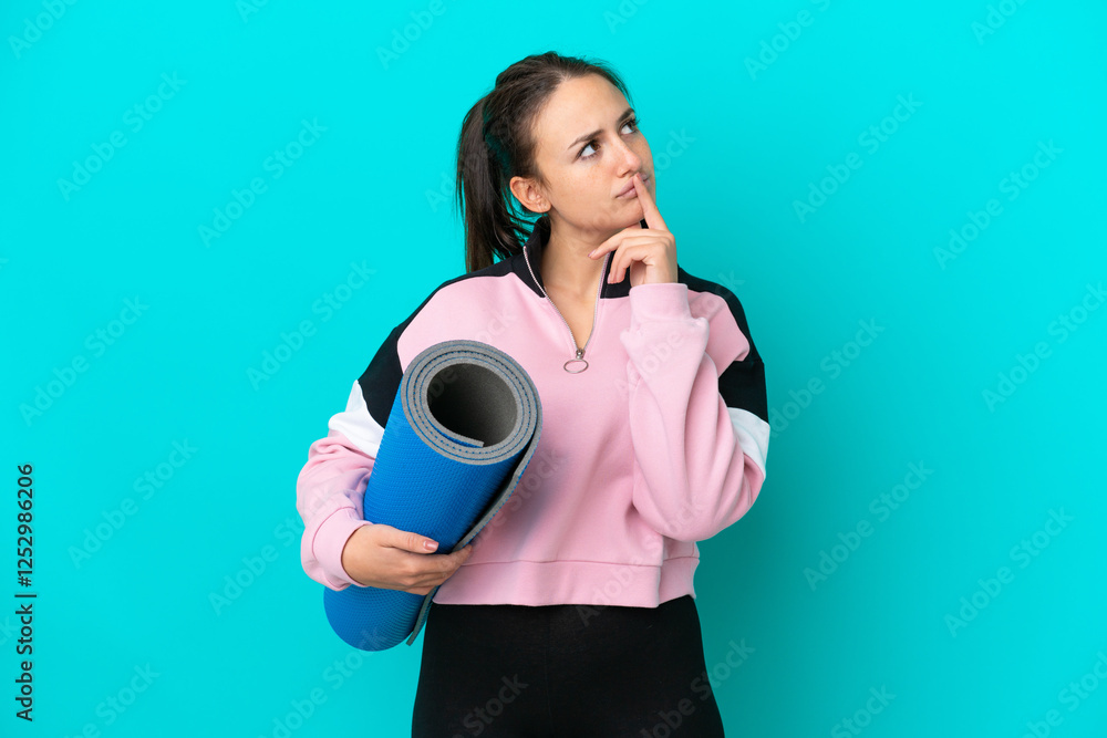 Sport Ukrainian woman going to yoga classes while holding a mat having doubts while looking up Sport Ukrainian woman going to yoga classes while holding a mat having doubts while looking up