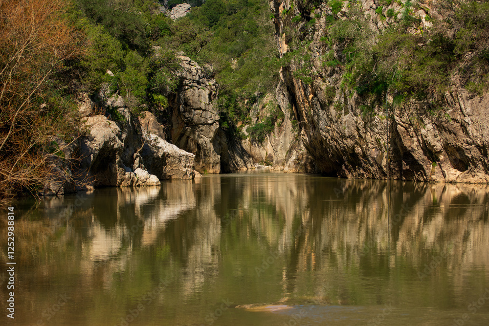 the calm waters of the river reflect the sharp peaks of the cañomn de las buitreras, malaga the calm waters of the river reflect the sharp peaks of the cañomn de las buitreras, malaga