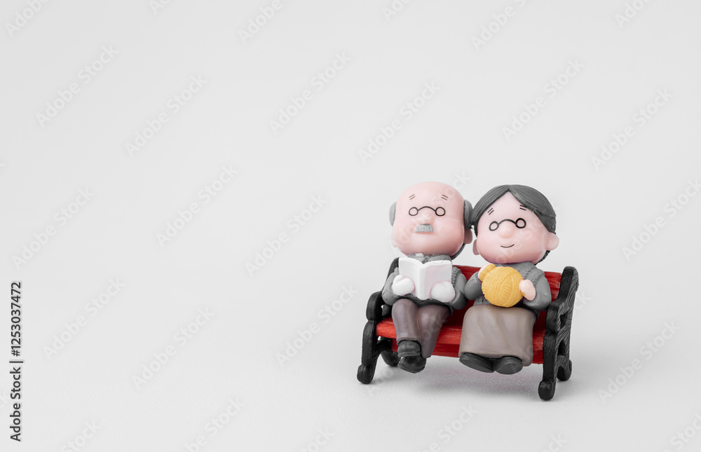 Elderly couple doll Wife sits in a chair on a white background. Concepts of financial planning and retirement. With copy space Elderly couple doll Wife sits in a chair on a white background. Concepts of financial planning and retirement. With copy space